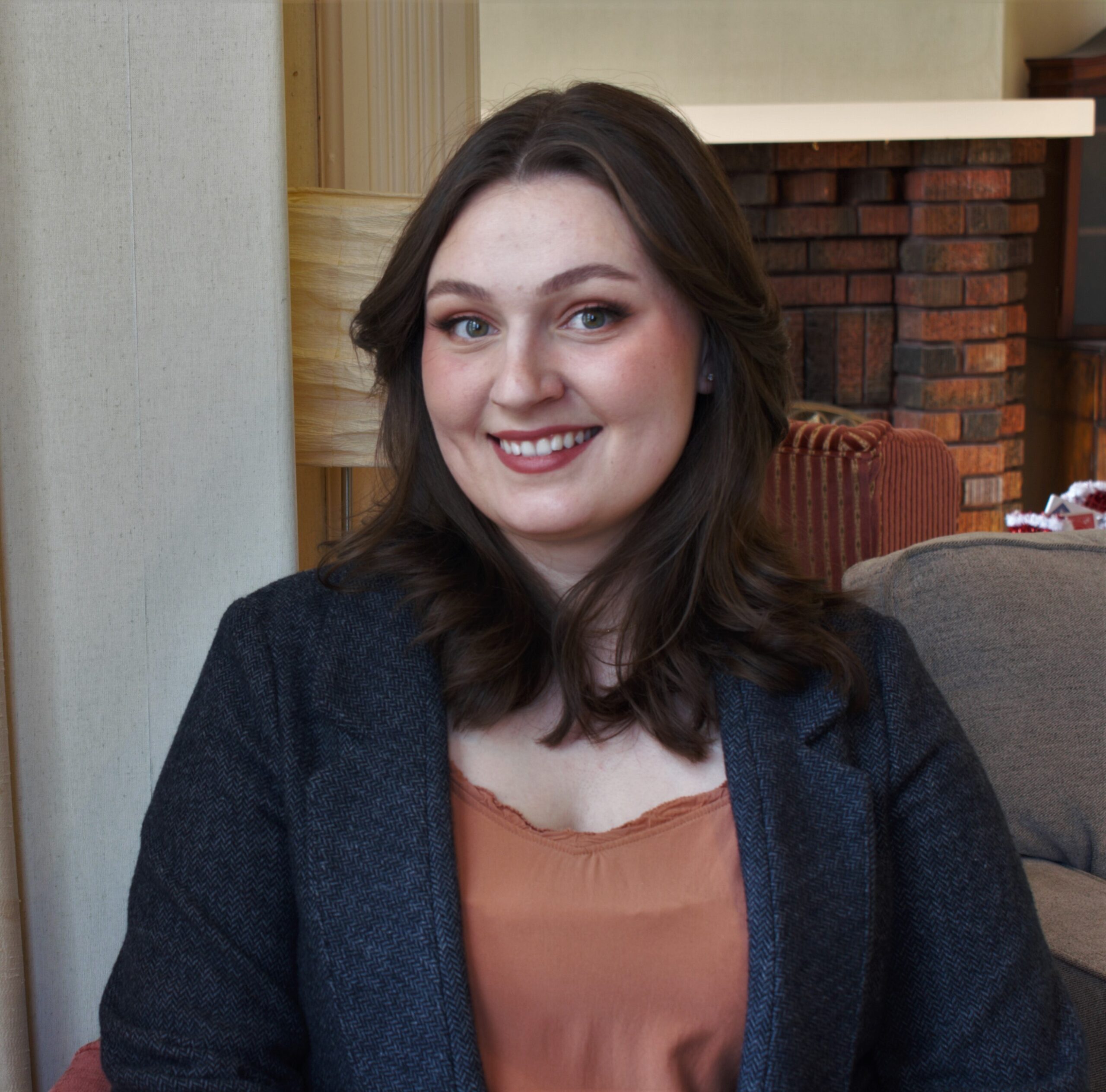 Portrait of Amy wearing an orange shirt and grey coat